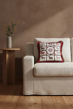 A cream slipcovered sofa in a warm, rustic room setting, featuring a decorative throw pillow with a red and white horse-themed pattern. A small wooden side table with a vase of yellow flowers sits to the left.