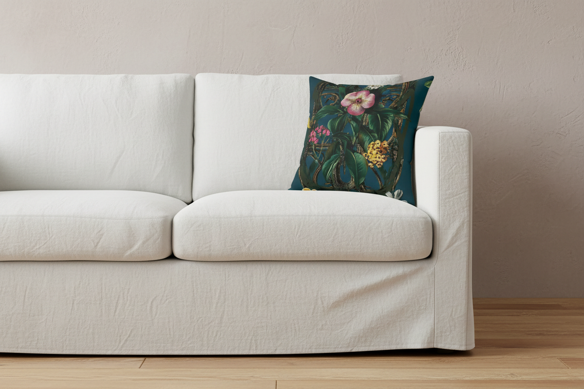 An olive green velvet sofa with vertical channel tufting in a styled room, featuring a dark teal floral throw pillow and a black side table with a vase.