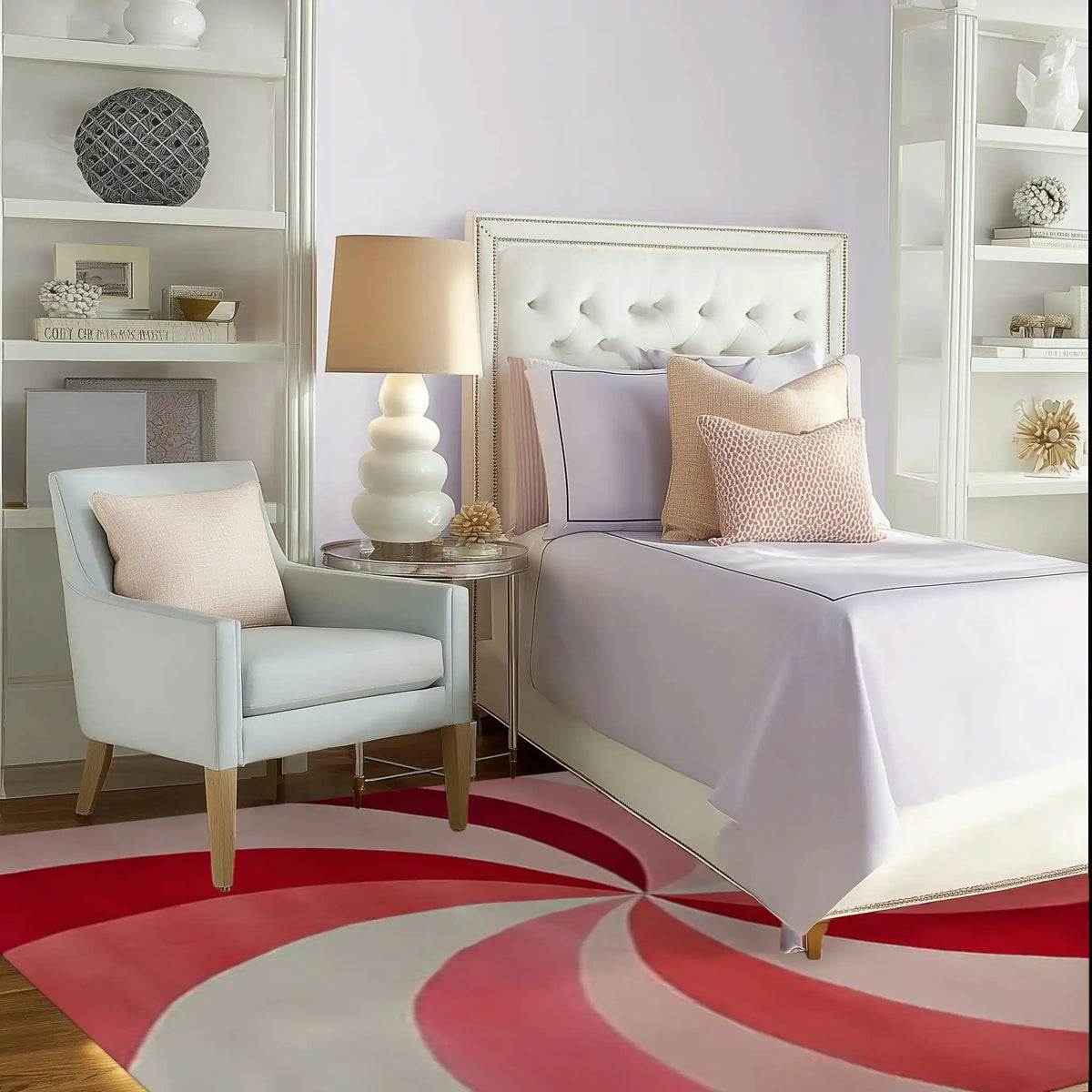 A stylish bedroom setting featuring the Blushing Pinwheel Hand Tufted Rug with a vibrant pink and red swirling pattern. The area rug adds a pop of color to the cozy space, making it perfect for both living room and office settings. The elegant wool rug complements the plush armchair and sophisticated décor, creating a warm and inviting atmosphere.