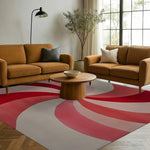 Stylish Blushing Pinwheel Hand Tufted Area Rug in a cozy living room setting with mid-century modern furniture. This wool rug features a vibrant red and pink pinwheel design, perfect for adding a pop of color to your office or living room space.