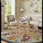 A beautifully decorated living room featuring a Botanical Radiance Round Hand Tufted Wool Rug. This elegant area rug, perfect for large living rooms, showcases a vibrant design with red and yellow botanical patterns. The round wool rug complements the classic decor, with a light-colored sofa, armchair, and coffee table enhancing the sophisticated ambiance.