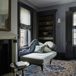 Decorative living room with a chaise lounge, bookshelf, persian rug, and fireplace.