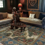 This elegant Castle Country Wool Hand Knotted Area Rug adds a vintage charm to the living room. The 8x10 rug features an intricate design with castle and floral patterns, perfectly complementing the classic furniture and warm lighting.