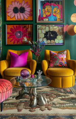 A cozy living room scene featuring a Castle Country Wool Hand Knotted Area Rug. The vibrant vintage rug is an 8x10 size, perfectly complementing the colorful artwork on the walls and the mustard yellow armchairs with bright pink pillows. This elegant living room area rug adds warmth and style to the space.