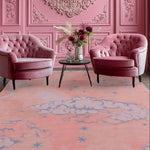 A beautifully designed hand tufted wool area rug featuring a pink sky with clouds and stars, adding a touch of elegance to a living room. The vintage-style rug complements the plush pink chairs and ornate wall, making it ideal for a cozy yet stylish atmosphere. Perfect for those seeking rugs for living room, area rugs for living room, or a wool rug with a unique design.