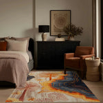 Coastal Silhouette Hand Tufted Area Rug in a bedroom setting, showcasing an abstract design with vibrant blues and warm oranges. Perfect for adding a touch of elegance to bedroom decor, this wool rug complements the cozy bed, stylish chair, and chic dresser, ideal for both bedrooms and living rooms.