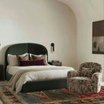 A cozy bedroom featuring a Countryside Charm Hand Knotted Area Rug with a vintage design. This square wool rug adds a touch of elegance to the living room or office space, complementing the upholstered bed and armchair perfectly.