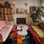 A stylish living room featuring a vibrant Crimson Curve Hand Tufted Wool Rug. The area rug adds a splash of color with its bold abstract pattern, perfect for large living rooms or as an 8x10 living room centerpiece. Surrounded by plush sofas and modern decor, this wool rug enhances the cozy atmosphere of the office space.