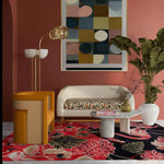 A vibrant living room featuring a Crimson Paradise Hand Tufted Area Rug with an abstract design in red and black hues. The wool rug adds a luxurious touch to the space, complementing the modern furniture and large wall art. Perfect for enhancing any living room area.