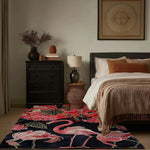 A cozy living room featuring a Crimson Paradise Hand Tufted Area Rug with vibrant red and pink flamingo designs, adding a splash of color to the neutral tones of the bedroom setting. This wool rug enhances the warm, inviting atmosphere, perfect for any living room area.
