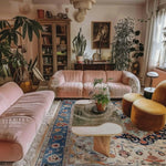 A cozy office space featuring a Cultural Essence Hand Tufted Area Rug with a vibrant abstract design. The wool rug adds warmth and style, complementing the plush pink sofas and the modern coffee table. Perfect for enhancing office interiors with elegant office rugs.