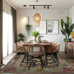 A stylish dining room featuring a beautifully designed area rug under a wooden dining table. The wool rug showcases vibrant geometric patterns, enhancing the room's decor. Natural light filters through sheer curtains, complementing the lush green plants and modern pendant lighting.