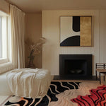 A stylish living room featuring a contemporary wool area rug with curved lines. The rug's abstract design adds a touch of modern elegance to the space, complementing the minimalist decor. Ideal for those seeking unique area rugs for living rooms, this piece enhances the overall aesthetic with its bold patterns and luxurious texture.