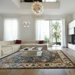 Elegant living room featuring a large, blue floral hand-knotted area rug with intricate patterns, complementing a modern white sectional sofa and a chic coffee table, under a stylish chandelier.