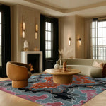 A contemporary area rug with an abstract design in vibrant shades of blue, orange, and pink, enhancing a stylish living room setting. The wool rug complements the modern decor with its bold pattern, making it an ideal choice for rugs in living rooms.