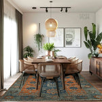 A beautifully styled dining room featuring the Ember Haven Hand Tufted Area Rug with a vintage design. This large living room wool rug showcases a captivating blend of orange and blue floral patterns, adding a touch of elegance and warmth to the space. Surrounded by chic wicker chairs and lush greenery, the rug perfectly complements the modern decor.