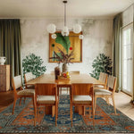 A beautifully decorated dining room featuring the Ember Haven Hand Tufted Rug, an exquisite area rug with a vintage design. The large living room rug is crafted from high-quality wool, showcasing a rich blend of blue and rust colors that enhance the warmth of the wooden furniture and the natural light streaming in from the window.