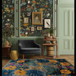 A vibrant living room featuring a hand-tufted wool rug with an Ethereal Garden Lullaby design. The large area rug showcases a floral pattern with vivid colors, adding a touch of elegance to the space. The rug enhances the hardwood floor and complements the stylish decor, including a plush gray chair and floral wallpaper, perfect for large living room settings.