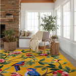 A vibrant, hand-tufted wool area rug featuring colorful birds and flowers on a yellow background, beautifully placed in a cozy living room. The living room area rug complements the neutral-toned furniture and natural light streaming through large windows, creating a warm and inviting atmosphere.