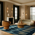 A stylish living room featuring a Fluid Motion Hand Tufted square area rug with a contemporary abstract design in shades of blue. The wool rug adds a modern touch to the room, complementing the elegant furniture and decor. Ideal for enhancing the aesthetics of living rooms and bedrooms, this contemporary rug is perfect for those seeking chic rugs for the bedroom or living room.