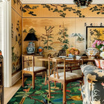 This vibrant living room features the 'Garden of Eden Hand Tufted Rug', a wool square area rug that perfectly complements the elegant decor. The large area rug showcases a lush, detailed botanical pattern that adds a touch of nature to the space. Ideal for offices or living rooms, this beautiful wool rug enhances the classic wooden furniture and intricate wall art, creating a harmonious and inviting atmosphere.