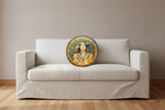 A round decorative throw pillow featuring an Art Nouveau style illustration of a woman with ornate jewelry, resting on a white slipcovered sofa in a minimalist room setting.