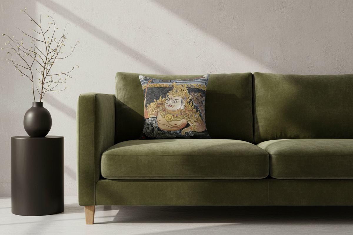 An olive green velvet sofa in a styled room setting, featuring a square throw pillow with a detailed traditional illustration of a golden-skinned deity on the back.