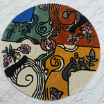 Round tufted rug with artistic design on a textured white surface. Nature's Kaleidoscope Hand Tufted Round Rug