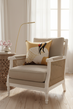 A brown leather armchair with matching ottoman in a warm living room setting, styled with a decorative pillow, a floor lamp, and a side table with white roses.
