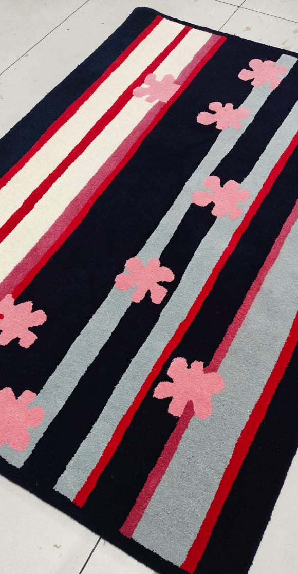 Rug with pink flower patterns and red, white, and gray stripes on a black background