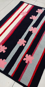 Rug with pink flower patterns and red, white, and gray stripes on a black background