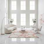 Modern living room with a pink and white patterned rug, white furniture, and large windows.