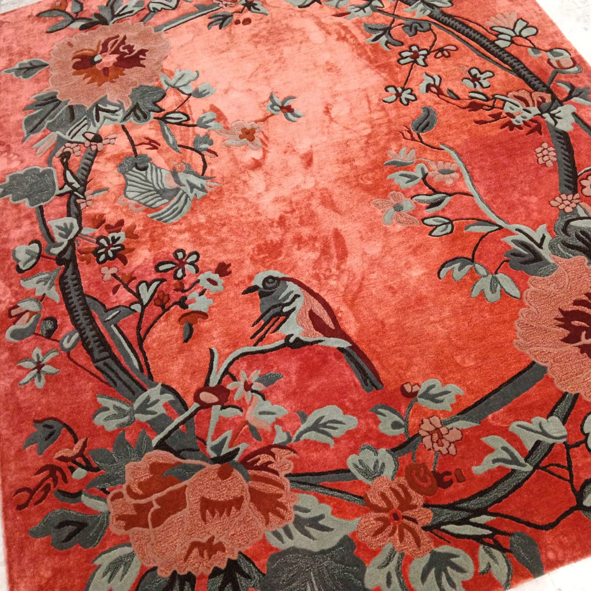Decorative rug with floral and bird pattern on a red background