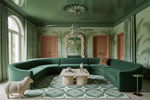 Luxurious living room with green walls, green geometric rug, sofa, and decorative elements.