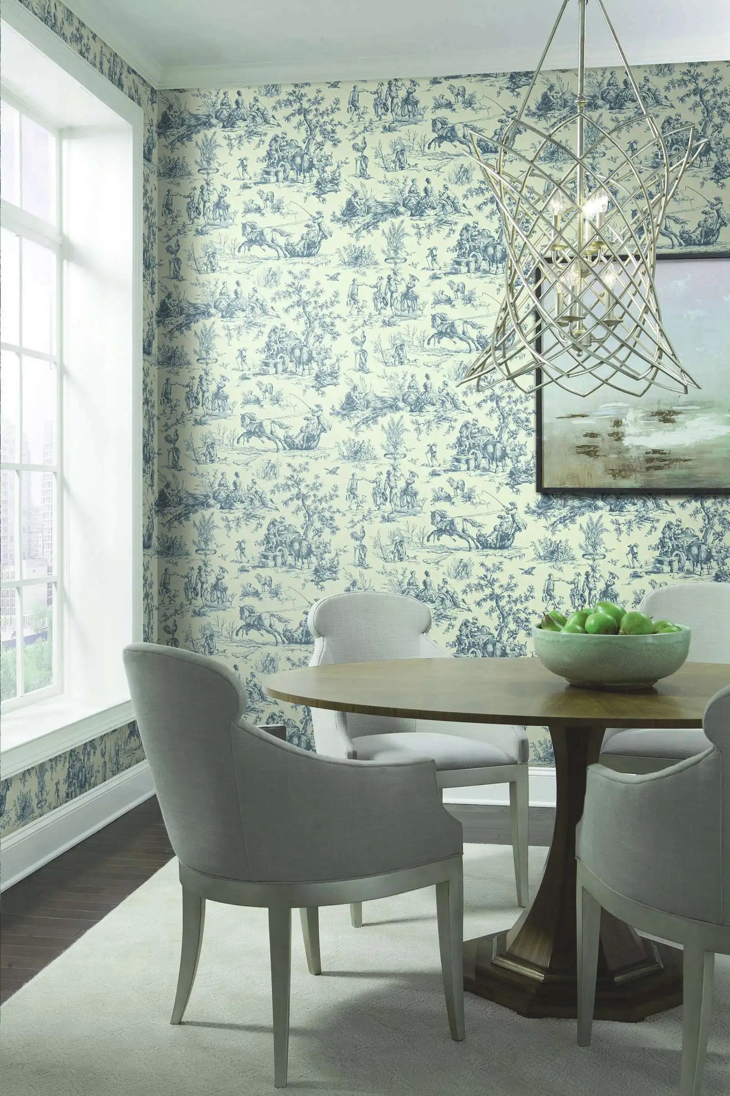 Dining room with blue and white toile wallpaper, wooden table, and white chairs.