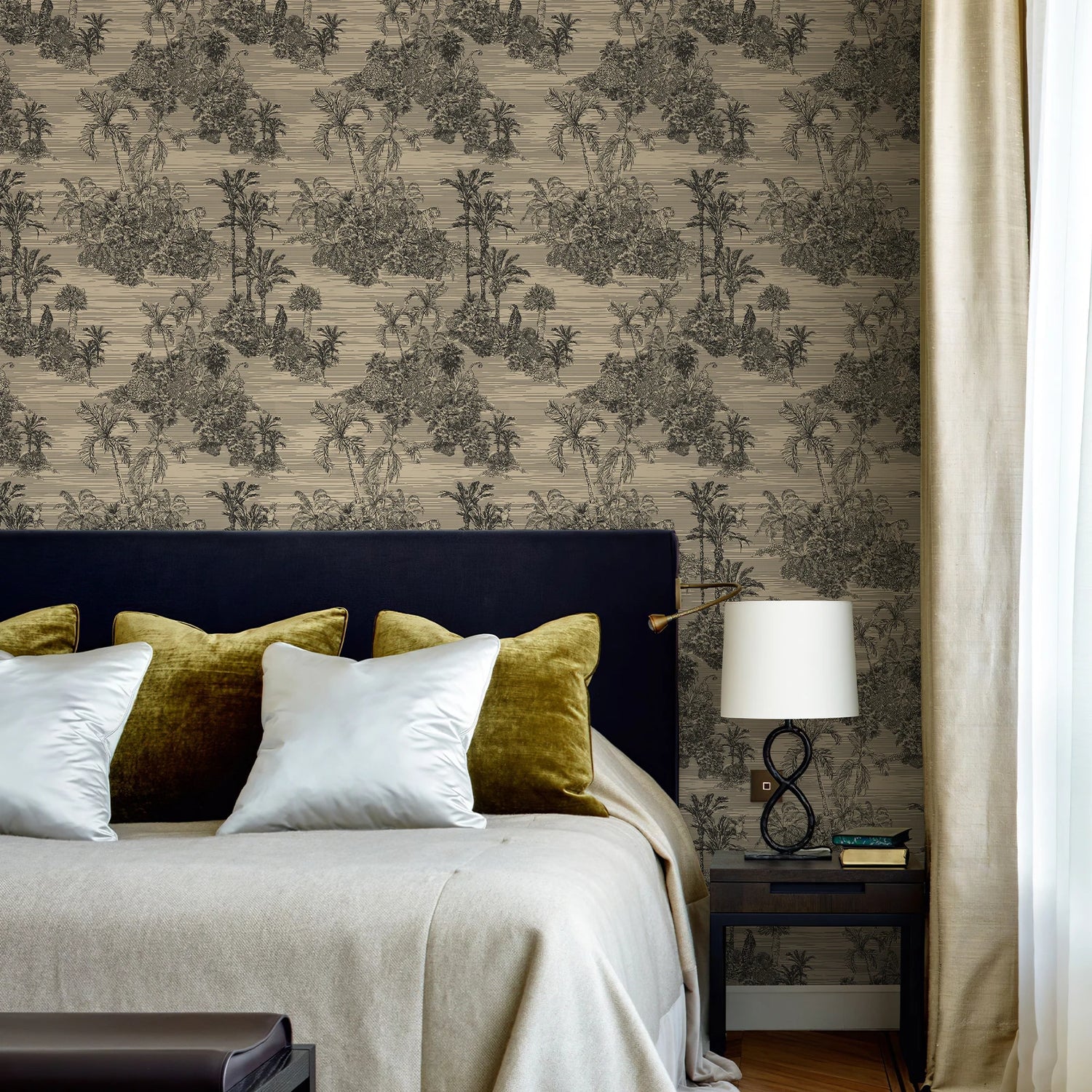 Bedroom with patterned wallpaper, bed with green and white pillows, and nightstand with lamp.