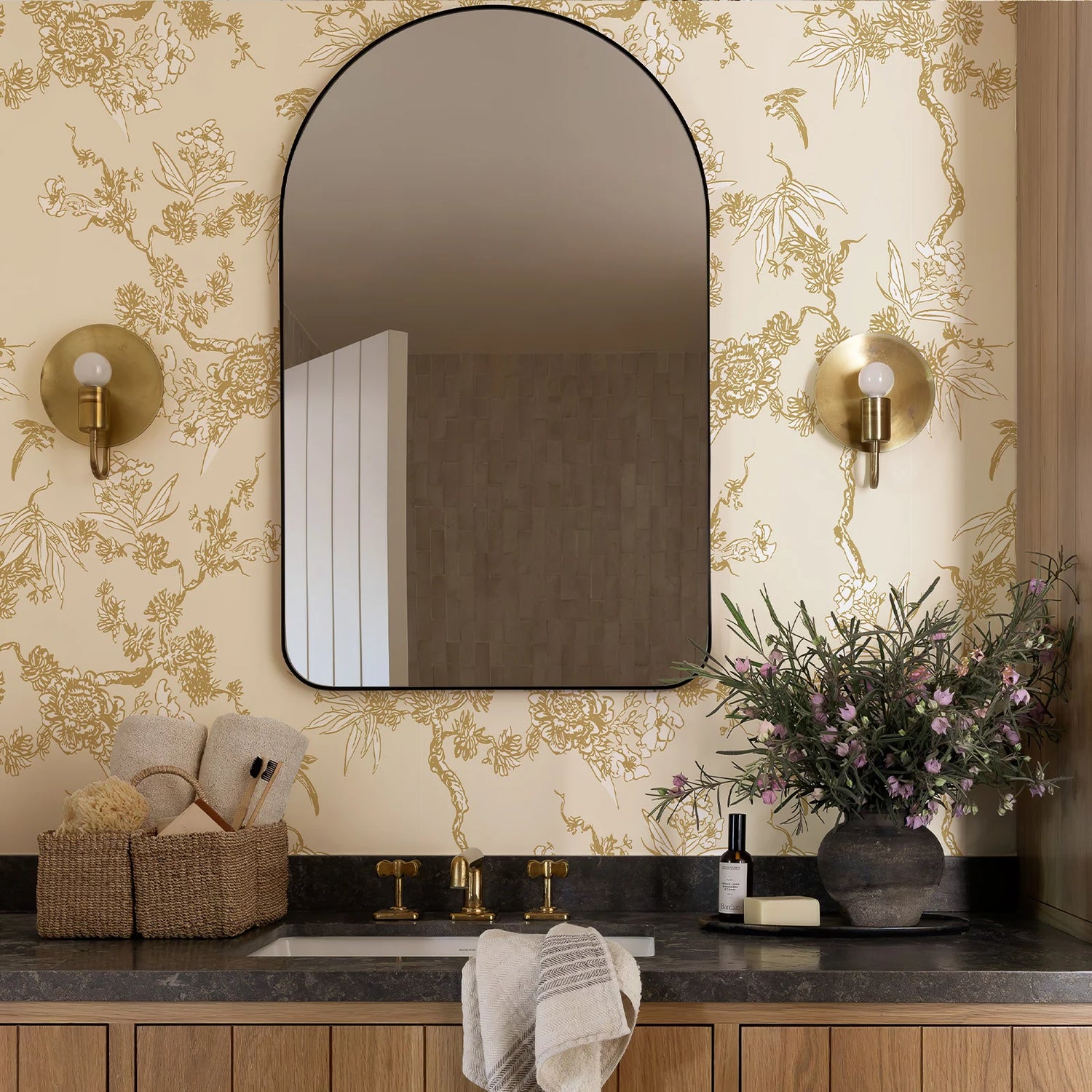 Bathroom with a large mirror, floral wallpaper, and decorative elements.
