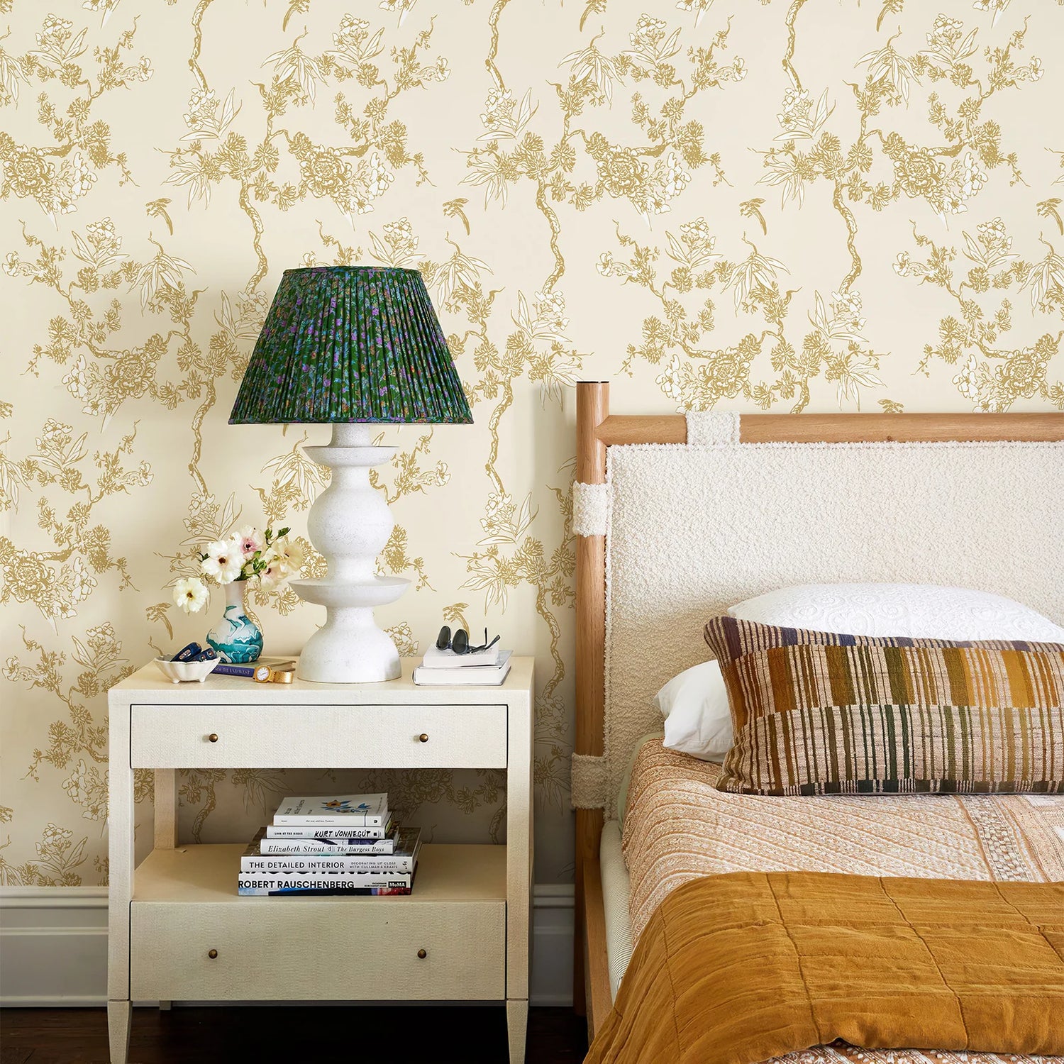 Bedroom with floral wallpaper, bed, and nightstand with lamp.