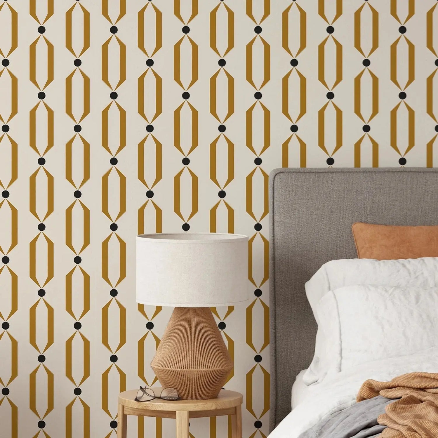 Bedroom with geometric patterned wallpaper, bed, and lamp.