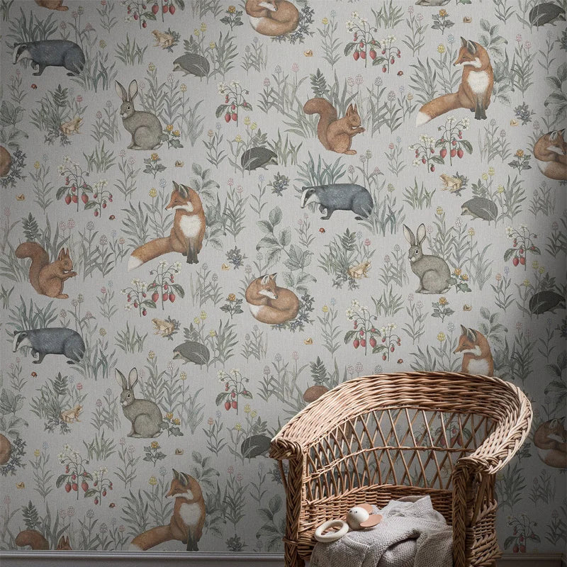 Wallpaper with forest animals pattern and a wicker chair in front.