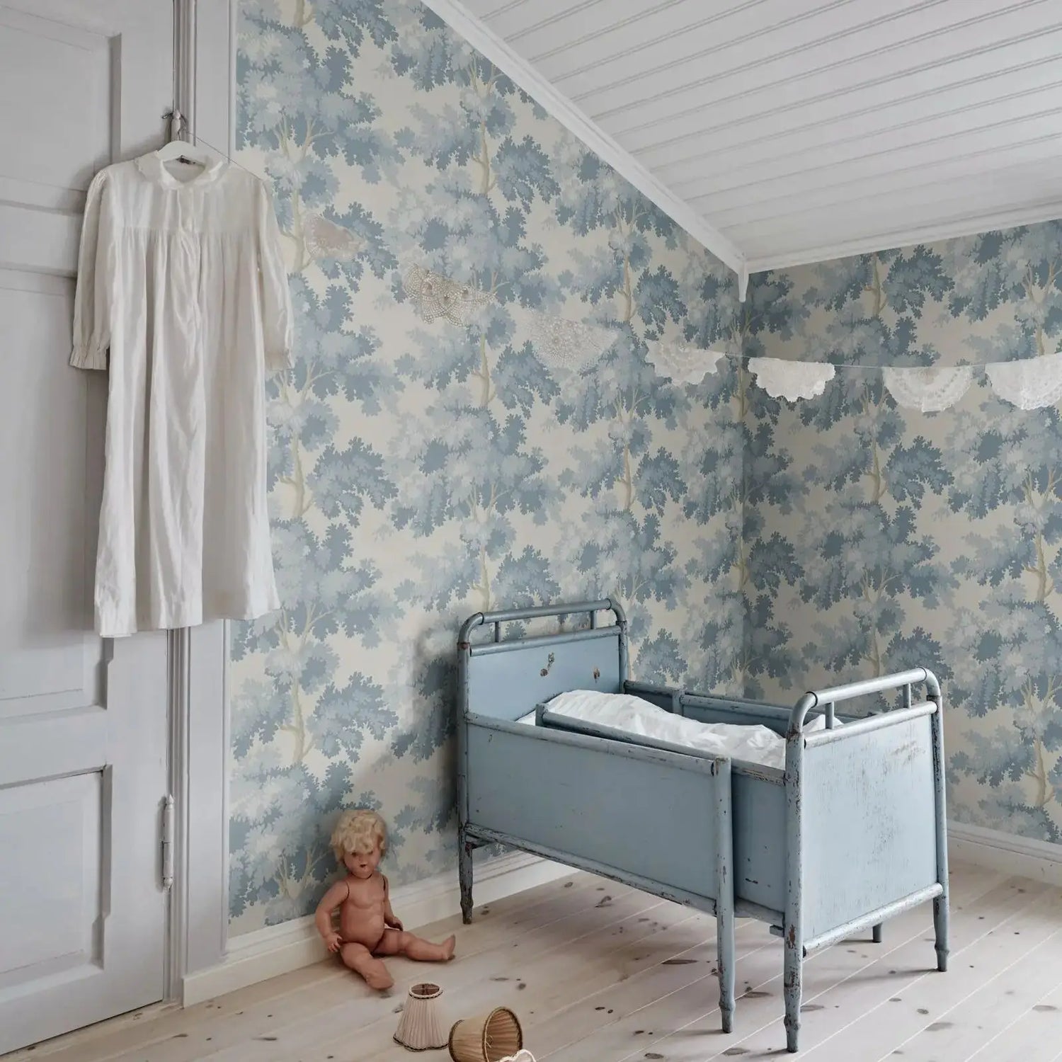 Vintage-style bedroom with floral wallpaper, a child's bed, and toys on a wooden floor.
