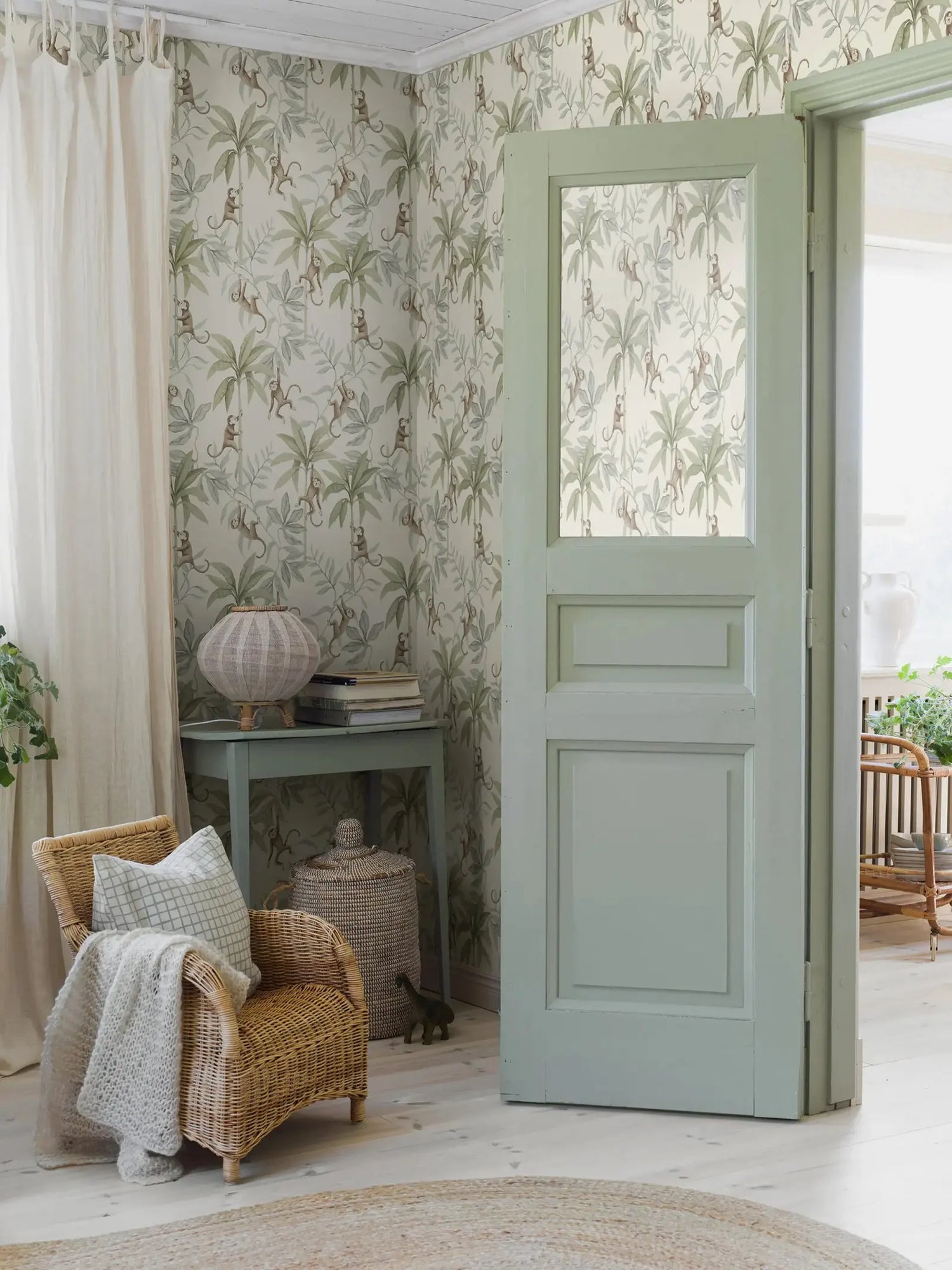 Living room with floral wallpaper, wicker chair, and open door leading to a garden.