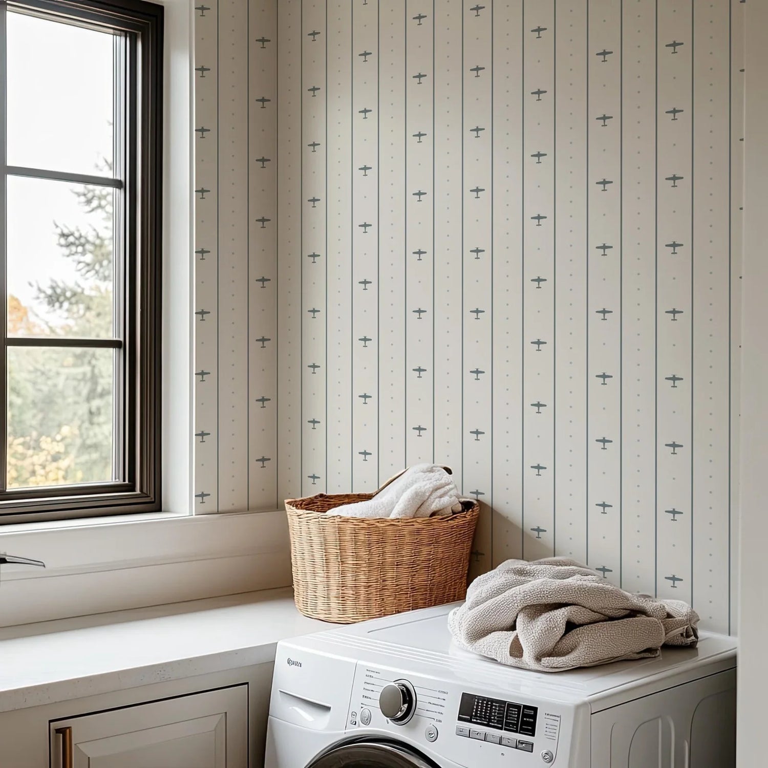 Laundry room with a washing machine, basket of clothes, and striped wallpaper.