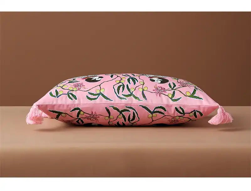 Throw pillow featuring a retro monkey charm design on a pink cushion cover with floral patterns and tassels.