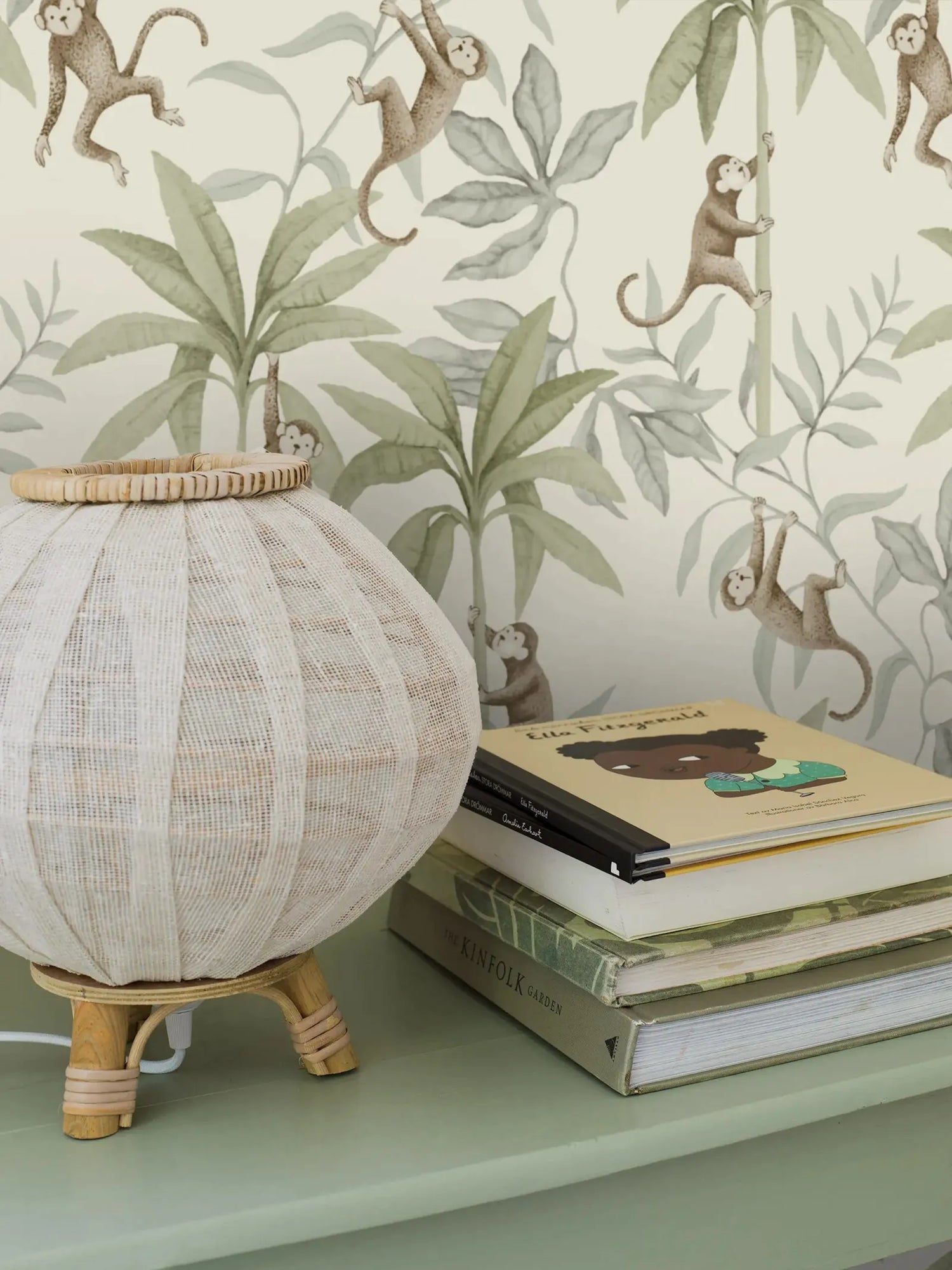 Decorative lamp on a shelf with books and a monkey-themed wallpaper in the background