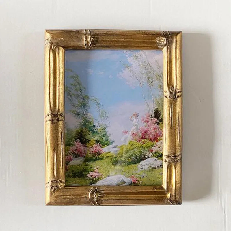 Framed painting of a garden scene with a gold frame on a white wall