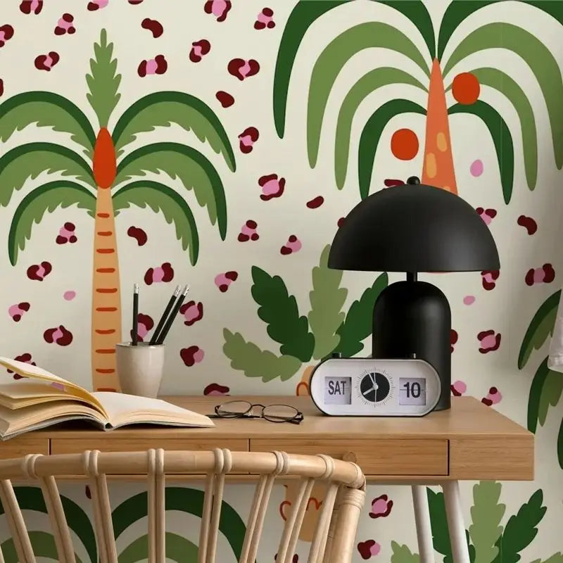 Desk with a black lamp and open book against a palm tree and heart-patterned wallpaper.