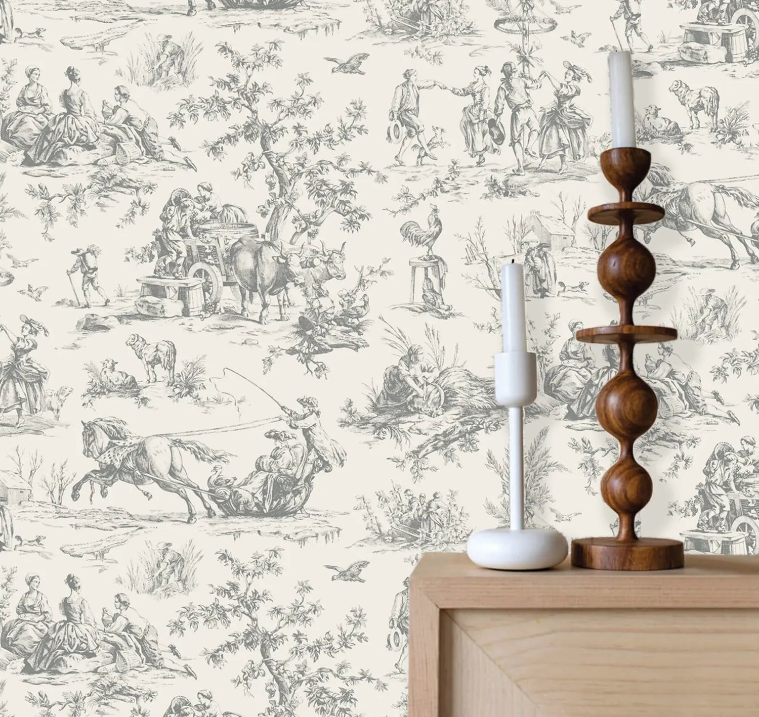 Wooden candlestick and white candle on a wooden surface with decorative wallpaper featuring illustrations of people and animals.