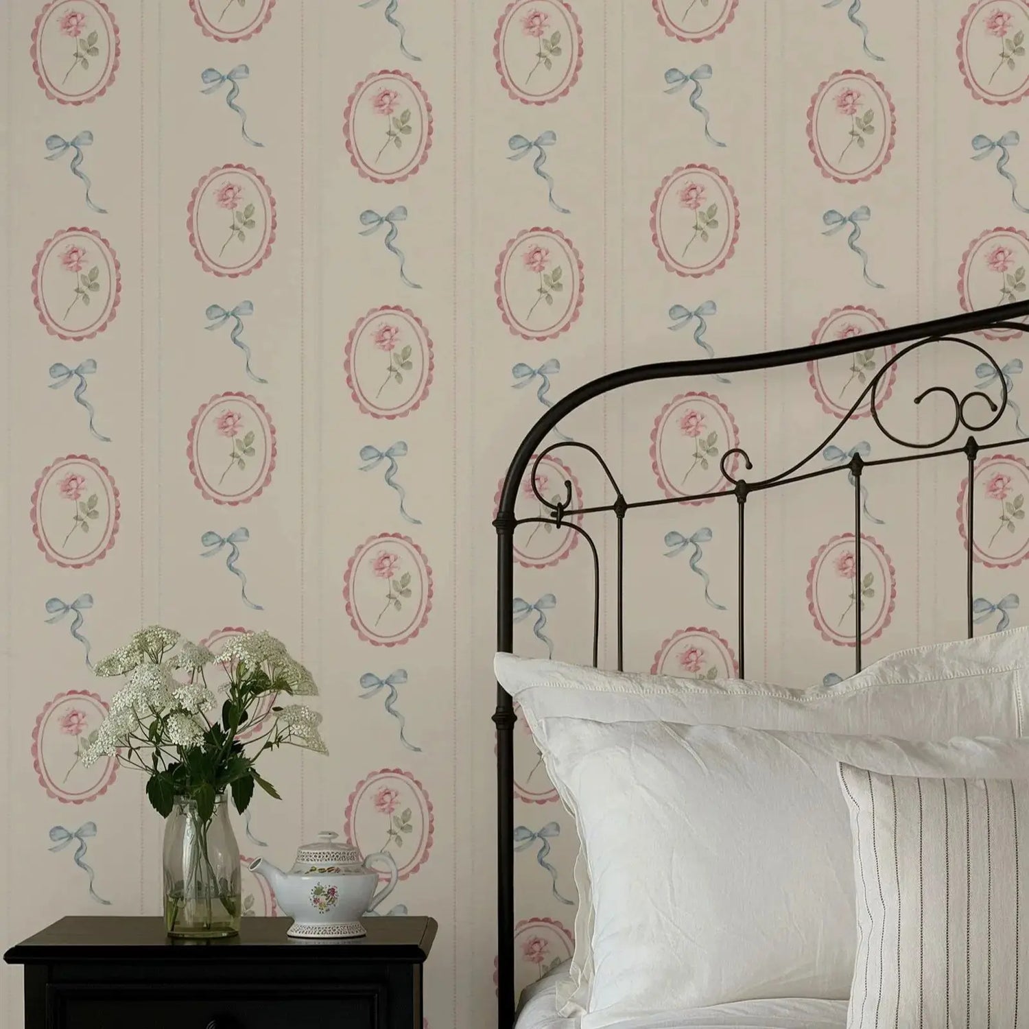 Bedroom with floral wallpaper, iron bed, and decorative items.