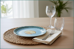 Poseidon's Journey Blue Scallop Shell Decorative Ceramic Plate on a woven charger with wine glasses.